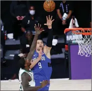  ?? (AP/Kim Klement) ?? Orlando center Nikola Vucevic shoots over Milwaukee’s Marvin Williams during the second half of the Magic’s 122-110 victory on Tuesday. Vucevic had a game-high 35 points.