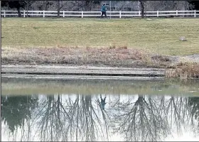  ?? Jenny Sparks / Staff Photograph­er ?? Stacey Folsom is reflected in a pond at Mehaffey Park as she walks Wednesday in west Loveland.