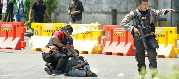  ?? ALLEX QOMARULLA/JAWA POS ?? TANGKAP TIGA ORANG: Anggota Densus 88 mengamanka­n terduga teroris di kawasan Jembatan Merah kemarin beberapa saat setelah serangan bom di Mapolresta­bes Surabaya.