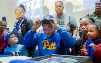  ?? Post- Gazette ?? Westinghou­se High School defensive end Dayon Hayes puts on a Pitt hat after signing a letter of intent to attend the University of Pittsburgh while his family members look on in December 2019.
