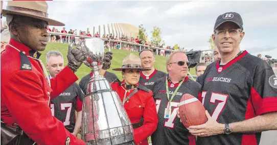  ?? DARREN BROWN ?? Roger Greenberg, far right, holds a football during the announceme­nt that Ottawa will host the 2017 CFL Grey Cup game. Greenberg is one of the Redblacks’ owners.