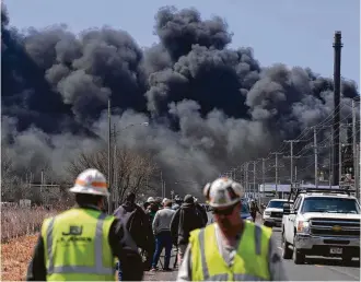  ?? Jules Ameel / AFP / Getty Images ?? Workers evacuate Thursday from an explosion and fire at the Husky Energy oil refinery in Superior, Wis. At least 11 people were injured, but no deaths were reported.