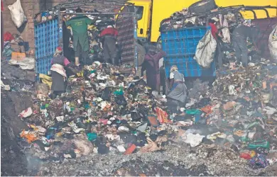  ?? MARK HOFFMAN / MILWAUKEE JOURNAL SENTINEL ?? Residents work with bare hands and no face masks searching for food and items they can resell while garbage is being dumped at Dandora, the massive smoldering pile of garbage in the Korogocho slum of Nairobi.