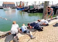  ??  ?? Kinder im Hafen von Oudeschild auf Krebsfang – das klappt mithilfe von frittierte­m Fisch an einer Schnur als Lockmittel.