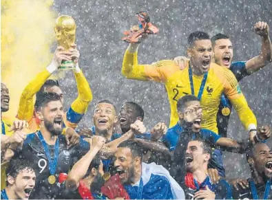  ?? JEWEL SAMAD/AFP/GETTY IMAGES ?? France’s players lift the World Cup trophy in a driving rain after winning the 2018 World Cup final match against Croatia at the Luzhniki Stadium in Moscow on Sunday. It was France’s second World Cup title, joining the one it earned in 1998.