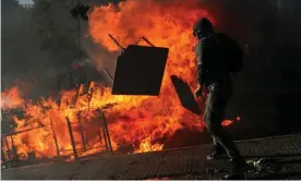  ??  ?? A demonstrat­or tosses furniture into an improvised bonfire during an anti-government protest in Santiago. Photograph: Edgard Garrido/Reuters