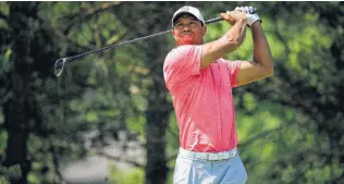  ?? Andy Lyons / Getty Images ?? Tiger Woods watches his tee shot on No. 2 during the third round of The Memorial. Woods briefly shared the lead until he bogeyed the 16th and 18th holes.