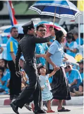  ?? ROJJANAMET­AKUL
SEKSAN ?? A policeman helps a family cross the road.