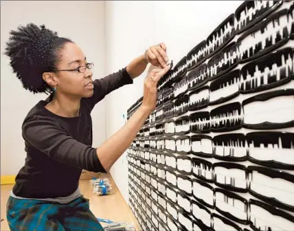  ?? Jeffrey Machtig
John Michael Kohler Ar ts Center ?? SONYA CLARK, seen installing a piece at a museum in Wisconsin, works with materials such as plastic combs.