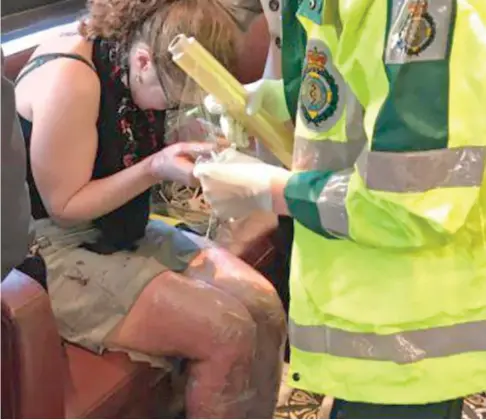  ??  ?? Suffering: A paramedic acts quickly to wrap protective film over the legs and hands of a badly burned woman