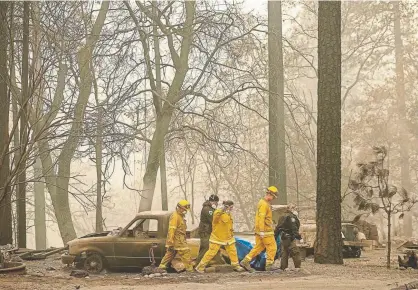  ?? Josh Edelson, AFP/Getty Images ?? Rescue workers carry a body from a burned property in Paradise, Calif., on Wednesday. At least 56 people have been killed in the Camp fire, and dozens are missing.