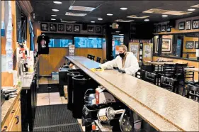  ?? BRIDGES SCOREBOARD ?? A worker with Tierra Environmen­tal wipes down the bar at Bridges Scoreboard in Griffith on Saturday morning.