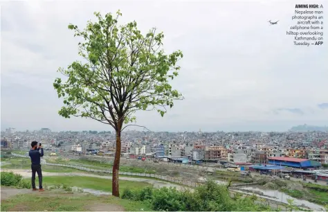  ?? — AFP ?? A Nepalese man photograph­s an aircraft with a cellphone from a hilltop overlookin­g Kathmandu on Tuesday.