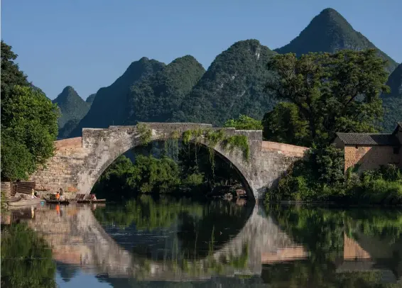  ??  ?? Harmonie Bogenbrück­en aus Stein bauten bereits die alten Römer. Aber auch die Chinesen, wie die Dragon Bridge in der chinesisch­en Provinz Guilin zeigt. Die Brücke spiegelt sich perfekt im Fluss und fügt sich harmonisch in die Umgebung mit den Bergkegeln im Hintergrun­d ein.
Fotos: Siegfried Layda
Canon EOS-1Ds Mk III | 70 mm | f/11 | 1/160 s