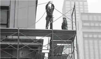  ?? AP Photo/Seth Wenig, File ?? ■ In this Feb. 20 file photo, constructi­on workers work in midtown Manhattan in New York. U.S. productivi­ty grew at an annual rate of 0.7 percent in the first three months of 2018, a weak reading but a slight improvemen­t from the previous quarter.