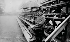  ?? Photograph: Sharples/Getty Images ?? A spectator shelters from the rain as he hopes for play to resume at a cricket match in 1924.