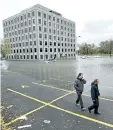  ?? JUSTIN TANG/THE CANADIAN PRESS ?? People walk past the flooded parking lot of the Pebb Building, located across from the Ottawa River, following a rain storm in Ottawa in October.