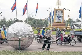  ??  ?? Conceptual artist Svay Sareth lugs “Ball and Chain” through Phnom Penh.