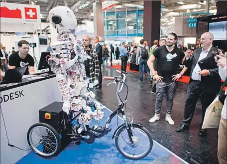  ?? Julian Stratensch­ulte AFP/Getty Images ?? A ROBOT sits on a bicycle at the booth of software maker Autodesk during the Hanover Fair technology event in April in Germany.