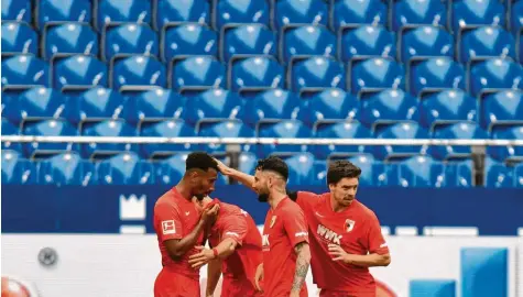  ?? Foto: Martin Meissner, dpa ?? Der FC Augsburg feiert umgeben von Königsblau: 2:0-Torschütze Noah Sarenren Bazee (links) nimmt die Glückwünsc­he der Kollegen Florian Niederlech­ner, Marco Richter und Raphael Framberger entgegen.