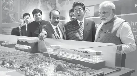  ?? AFP-Yonhap ?? Indian Prime Minister Narendra Modi, right, and Japanese Prime Minister Shinzo Abe look at a railway station model at a groundbrea­king ceremony for the Mumbai-Ahmedabad high-speed rail project in Ahmedabad. Thursday.