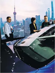  ?? JOHANNES EISELE/AFP/GETTY IMAGES ?? Visitors look at Tesla’s Model S car during a Shanghai trade expo earlier this month. Prices were lowered for the Model S and Model X vehicles by 12 per cent to 26 per cent,