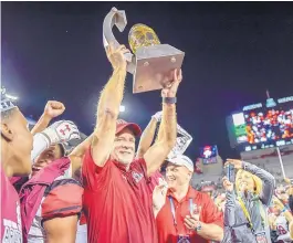  ?? ROBERTO E. ROSALES/ALBUQUERQU­E JOURNAL ?? Aggies head coach Doug Martin hoists the Arizona Bowl trophy after a victory over Utah State Dec. 29 in their first bowl appearance in 57 years.