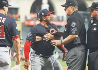  ?? Mike Ehrmann, Getty Images ?? Nationals manager Dave Martinez has to be restrained after being ejected for arguing an interferen­ce call during the seventh inning of Game 6 on Tuesday night.