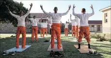  ??  ?? A group of inmates prepare for a series of sun salutation­s, which is a sequence of 12 postures done twice.