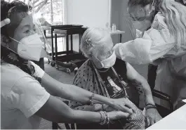  ?? MARTA LAVANDIER AP ?? Patricia Wasserman holds Hermina Levin’s hand as nurse Eva Diaz administer­s the Pfizer-BioNTech COVID-19 vaccine at John Knox Village onWednesda­y in Pompano Beach.