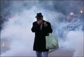  ?? (AP/Petr David Josek) ?? A bystander moves through smoke and tear gas Tuesday during a protest against vaccinatio­ns and coronaviru­s measures in Ljubljana, Slovenia.