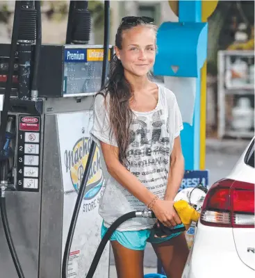  ?? Picture: ANNA ROGERS ?? COMPARING PRICES: Elena Fueger fills up at Machans Beach. She tries to use the internet to find the cheapest fuel, but says many sites are not reliable.