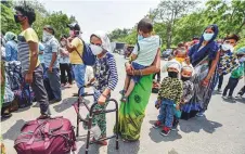  ?? PTI ?? A girl waits along with other migrants to get screened
■ before boarding a bus for a railway station in east Delhi.