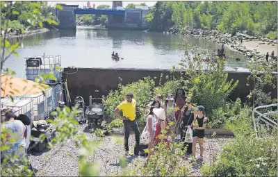  ?? [MICHAEL NOBLE JR. PHOTOS/THE ASSOCIATED PRESS] ?? A group of Kickstarte­r interns are led through the Swale Garden in New York. The garden is an old constructi­on barge planted with vegetables, apple trees and fragrant herbs that gives New Yorkers a chance to pick their own dinners.