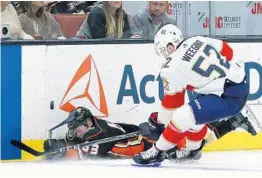  ?? VICTOR DECOLONGON/GETTY IMAGES ?? Kevin Roy of the Anaheim Ducks falls to the ice near the side boards against Mackenzie Weegar of the Panthers during Sunday’s game in Anaheim. The Ducks got the victory, 3-2.