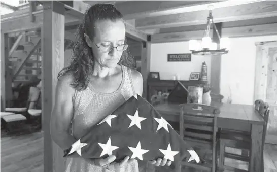  ?? KAREN PULFER FOCHT/AP ?? Gretchen Catherwood holds the flag that draped the casket of her son, Marine Lance Cpl. Alec Catherwood, in Springvill­e, Tennessee, on Aug. 18.