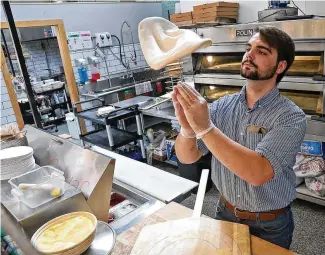  ?? BILL LACKEY / STAFF ?? Ryan Thomas, an employee of Crust & Company in the Springfiel­d Cohatch, makes a pizza for a customer Thursday.