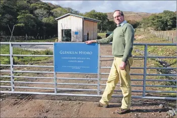  ?? 01_A44hydro01 ?? Kenneth with the Glenkiln Hydro sign showing the date of commission with the powerhouse in the background.