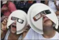  ?? THE ASSOCIATED PRESS ?? Annie Gray Penuel and Lauren Peck, both of Dallas, wear their makeshift eclipse glasses at Nashville’s eclipse viewing party ahead of the solar eclipse at First Tennessee Park on Monday, Aug. 21, 2017, in Nashville, Tenn.