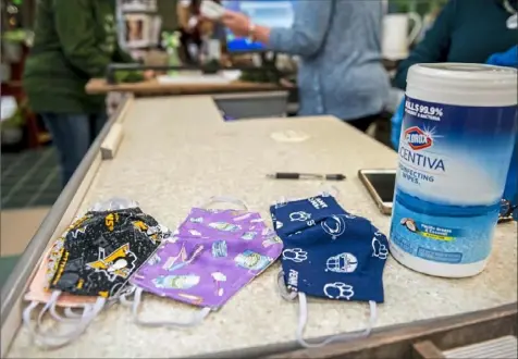  ?? Michael M. Santiago/Post-Gazette ?? Face masks sit on a counter next to disinfecta­nt wipes May 8 at Nells Crafts at Cranberry Mall in Cranberry, Venango County.