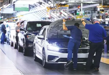  ?? STAFF FILE PHOTO ?? Volkswagen employees check items under the hood of a Passat sedan before it is driven off the assembly line at the Chattanoog­a plant.