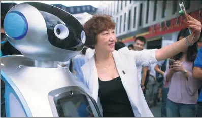  ?? TAN QINGJU / FOR CHINA DAILY ?? A visitor takes a picture with a smart robot at the launch of a comprehens­ive technology and financial services center sponsored by China Science and Merchants Capital Management Ltd in Guangzhou, Guangdong province.