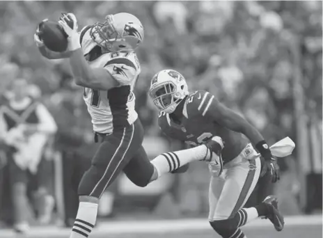  ?? RICK STEWART/GETTY IMAGES ?? Patriots tight end Rob Gronkowski hauls in a Tom Brady offering as the Bills’ Justin Rogers looks on. Buffalo’s D gave up an astounding 580 yards.