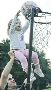  ??  ?? Olivia Thompson of Warragul, 2, puts the netball in the basket with a little help from her dad Niall.