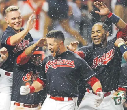  ?? Tony Dejak, The Associated Press ?? Cleveland Indians catcher Yan Gomes, center, is mobbed by teammates after hitting a three-run, walk-off homer with two outs in the ninth inning Tuesday night at Progressiv­e Field to defeat the Rockies 4-1.