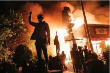  ?? AP Photo/John Minchillo ?? Protestors demonstrat­e outside of a burning fast food restaurant Friday in Minneapoli­s. It was the third consecutiv­e day of unrest over the death of George Floyd, a black man who died in police custody Monday.