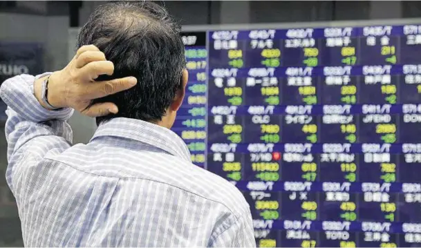  ??  ?? BOARD GAME: A man watches Nikkei share prices change on an electric board of a securities firm in Tokyo, Japan