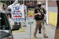  ?? Ted S. Warren/Associated Press ?? ■ A person who said he goes by the name James Madison carries a rifle as he walks Saturday near what has been named the Capitol Hill Occupied Protest zone in Seattle. Madison is part of the volunteer security team that has been working inside the CHOP zone and said he and other armed volunteers were patrolling Saturday to keep the area safe. A pre-dawn shooting Saturday near the area left one person dead and critically injured another person, authoritie­s said Saturday.