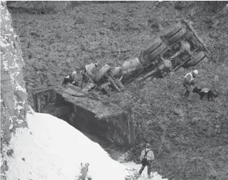  ?? GRAHAM HUGHES/THE CANADIAN PRESS ?? Rescue team members search for missing workers in a quarry at L’Epiphanie, Que., on Tuesday after a landslide swept vehicles into the quarry. Two workers were believed to have been buried in the gravel.