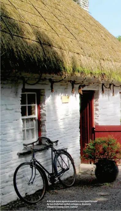  ??  ?? A bicycle leans against a wall in a courtyard formed by two thatched roofed cottages in Bunratty Village in County Clare, Ireland